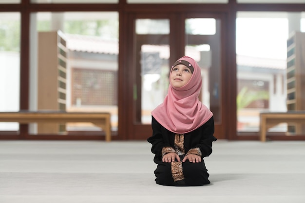 A menina muçulmana está rezando na mesquita