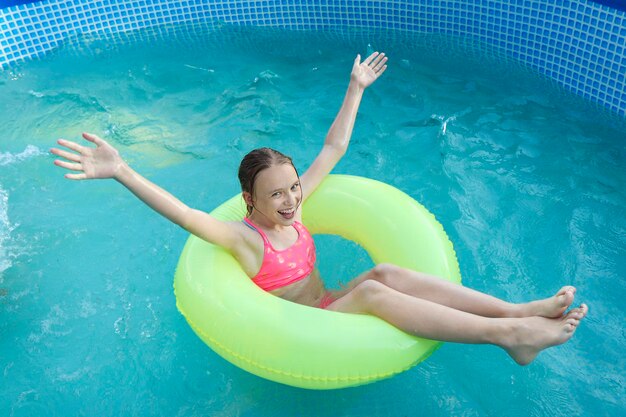 A menina nada alegremente na piscina no verão