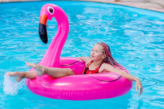 A menina nada em um flamingo inflável
