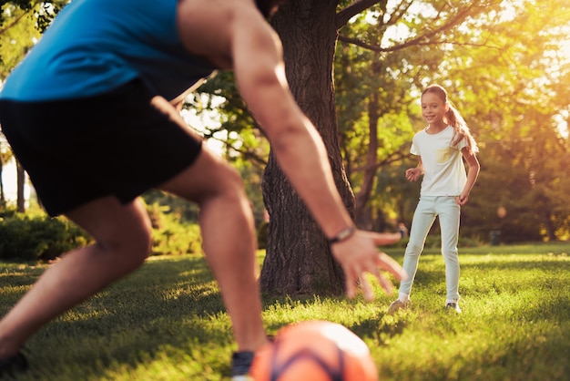 A menina no terno contestado leve joga o futebol com seu pai.