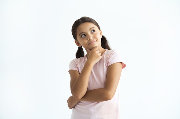 A menina pensativa em pé no fundo branco