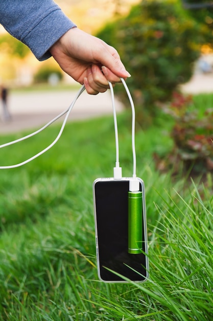 A menina prende pelo cabo um smartphone e um banco externo do poder ao carregar