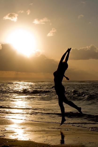 A menina que salta no nascer do sol na praia