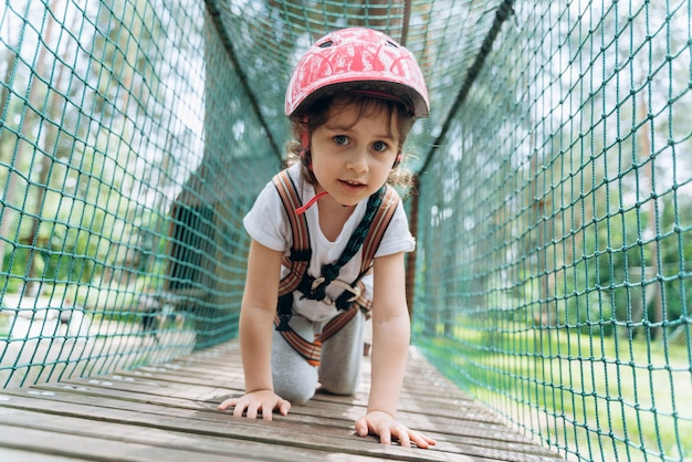 A menina rasteja de joelhos no teleférico. A criança passa ativamente o tempo