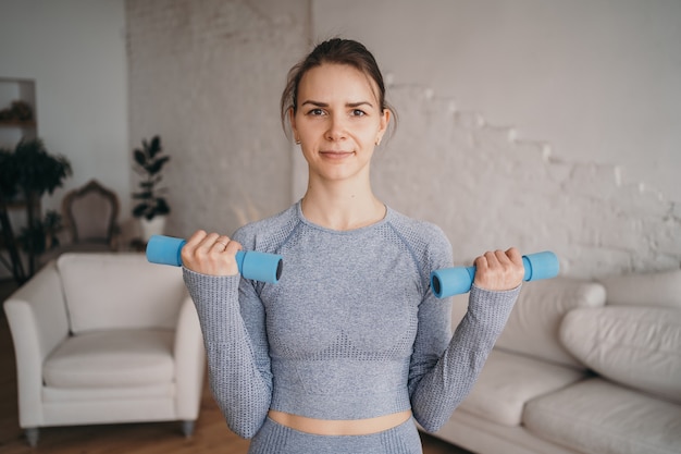 A menina realiza exercícios para as mãos em casa fazendo esportes em casa online estilo de vida saudável exercícios com halteres em casa