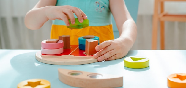 A menina recolhe classificador de madeira multi-colored Brinquedos naturais de madeira seguros para crianças