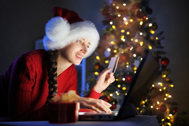 A menina se prepara para o Natal e encomenda presentes pela Internet com cartão de crédito