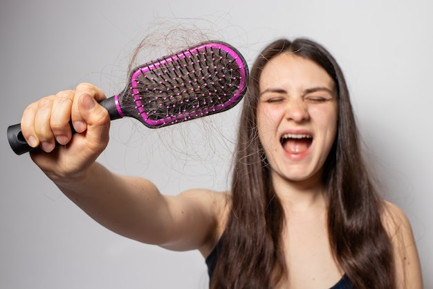 A menina segura um pente para cabelo com cabelo caído