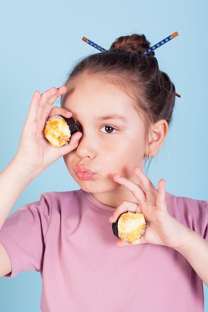 A menina segurando os pãezinhos tem cara de binóculo Entrega a domicílio de comida japonesa Sobre um fundo azul em um vestido rosa Cabelo comprido encaracolado É ridículo e estúpido