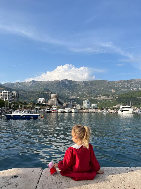 A menina senta-se em um cais com vista para a cidade