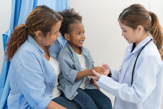 A menina senta-se na cama do paciente para o médico