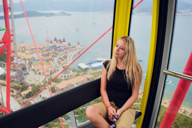 A menina senta-se no estande da roda gigante.