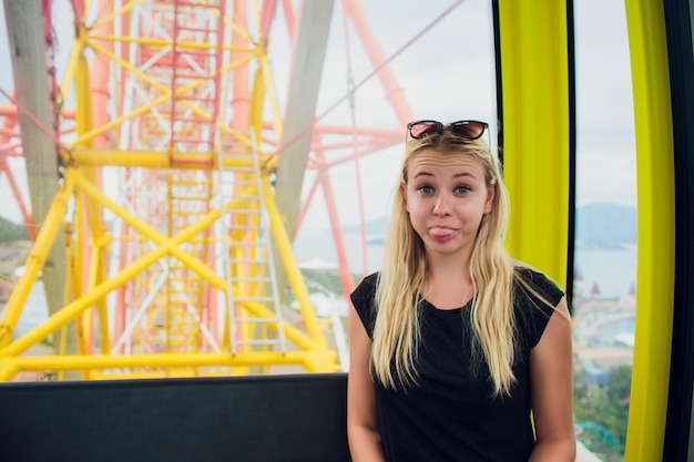 A menina senta-se no estande da roda gigante.