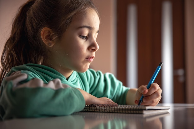 Foto a menina séria escreve com uma caneta em um caderno