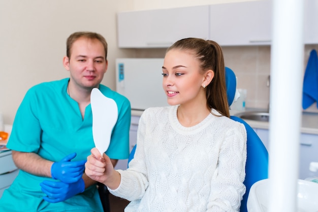 A menina sorri em odontologia. modelo de corridas de dentista de pacientes na Clínica Odontológica