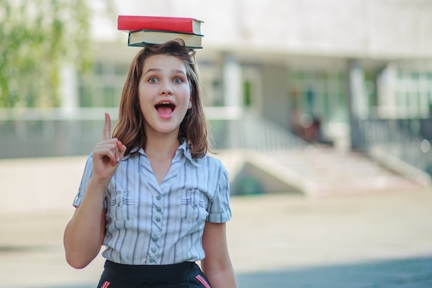 A menina tem dois livros, vermelho e verde na cabeça