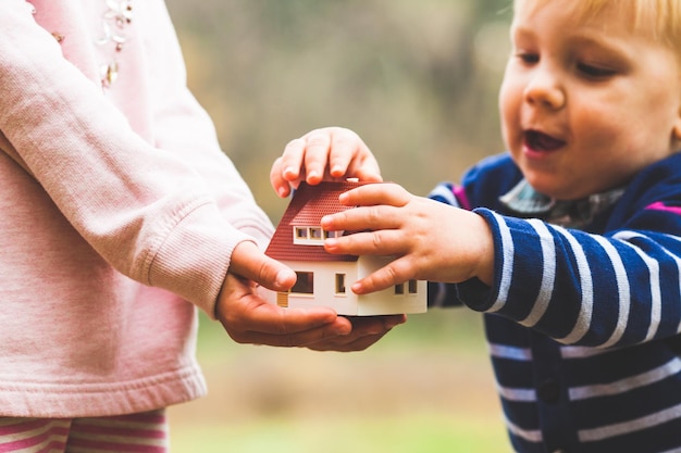 A menina tem uma pequena casa nas mãos e o menino é tocá-la. O conceito de adoção