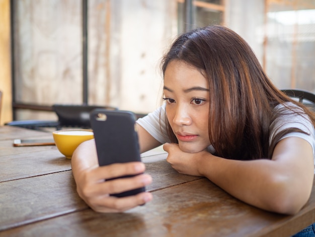 A menina triste está esperando uma ligação ou mensagem de texto do namorado. Sentado sozinho e ansioso em uma cafeteria