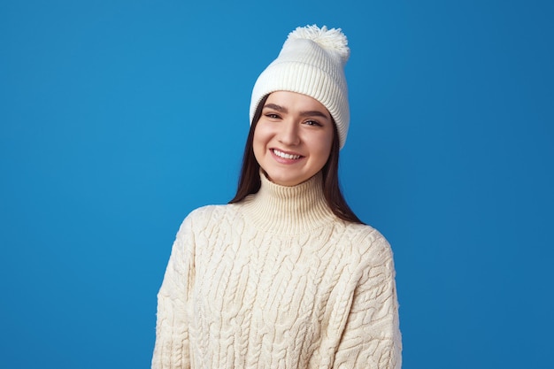 A menina usa um chapéu quente e um suéter de tricô grande e se sente feliz aproveitando o inverno