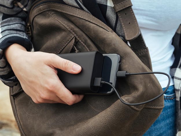 A menina usa um smartphone conectado ao banco de energia