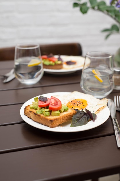 A mesa com café da manhã de sanduíches e ovos fritos copos de água com limão