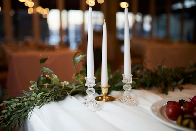 A mesa de jantar é decorada com velas brancas em castiçais e flores