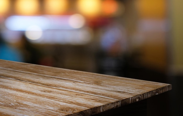 A mesa de madeira vazia na frente do fundo desfocado abstrato da cafeteria pode ser usada para exibição ou montagem de seus produtos mock up para exibição do produto