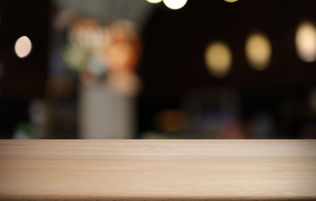 A mesa de madeira vazia na frente do fundo desfocado abstrato da cafeteria pode ser usada para exibição ou montagem de seus produtos Mock up para exibição do produto