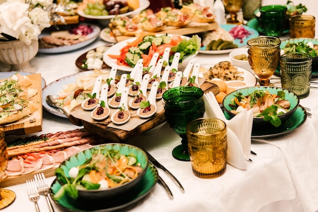 A mesa redonda branca é preenchida com uma grande quantidade de comida e vários lanches em uma luxuosa mesa interior definindo foco seletivo