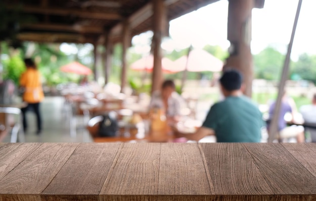 A mesa vazia de madeira escura na frente do fundo bokeh desfocado abstrato do restaurante pode ser usada para exibir ou montar seus produtos Mock up para espaço