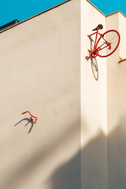 A metade traseira de uma bicicleta vintage e um guidão vermelho preso à parede de um bloco minimalista