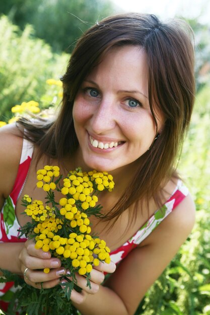 A moça cheira flores amarelas no campo