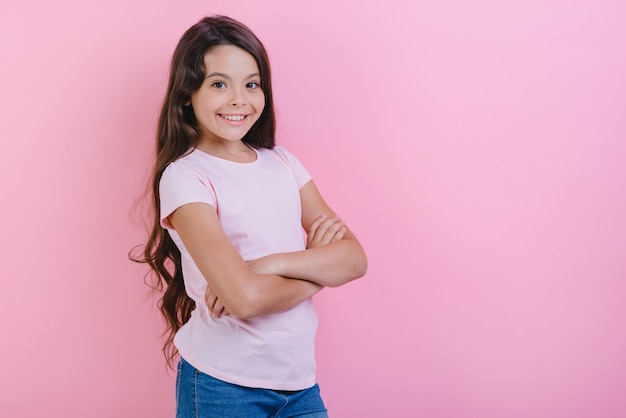 A moça de sorriso com mãos dobradas está vestindo no t-shirt que olha a câmera.