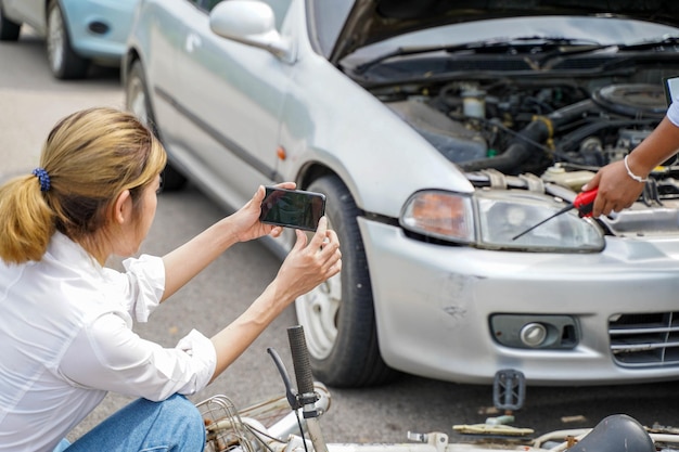 A motorista de close-up está usando telefones celulares para tirar fotos como prova de reivindicações de seguro com a seguradora de automóveis