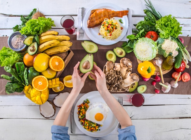 A mulher à mesa de jantar com alimentos orgânicos, a vista de cima.