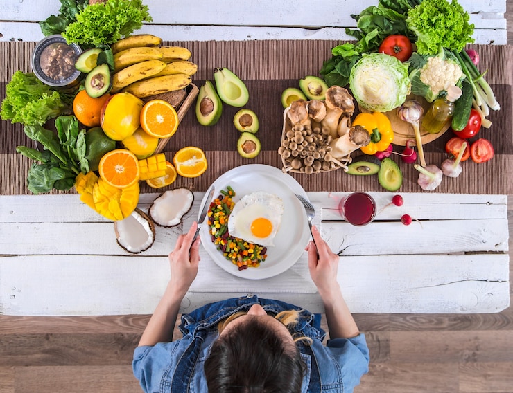 Foto a mulher à mesa de jantar com alimentos orgânicos, a vista de cima.