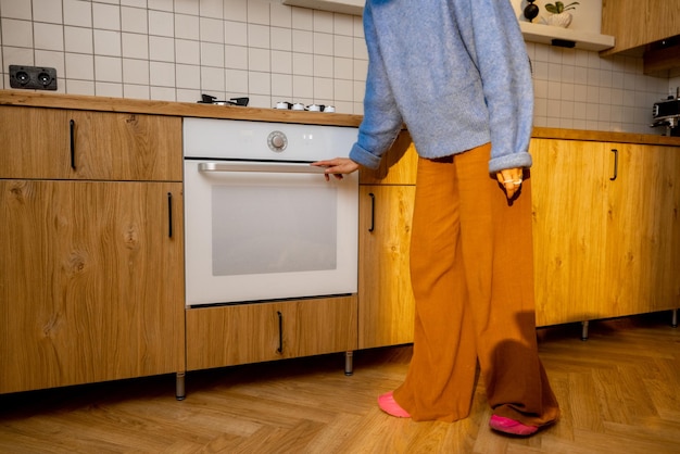 A mulher abre um forno na cozinha