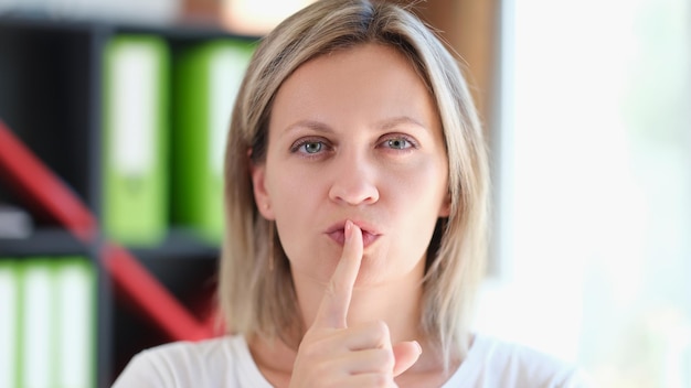 Foto a mulher adulta mantém o dedo nos lábios e gesticula para ficar em silêncio e manter a conspiração secreta