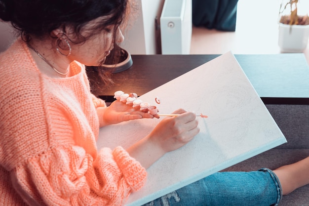 A mulher adulta pintando por números cores pastel desenhando na tela