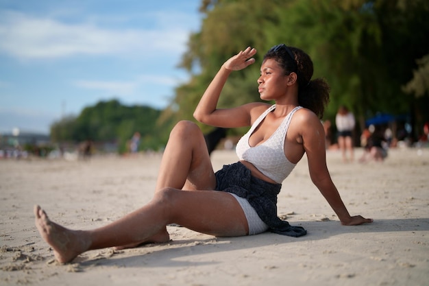 A mulher africana senta-se na praia O retrato sexy da senhora africana viaja ping e relaxa no verão com a natureza tropical