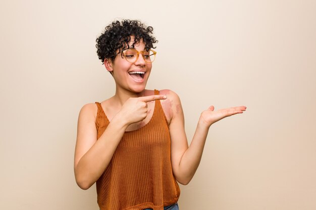 A mulher afro-americano nova com a marca de nascimento da pele excitou guardar um espaço da cópia na palma.