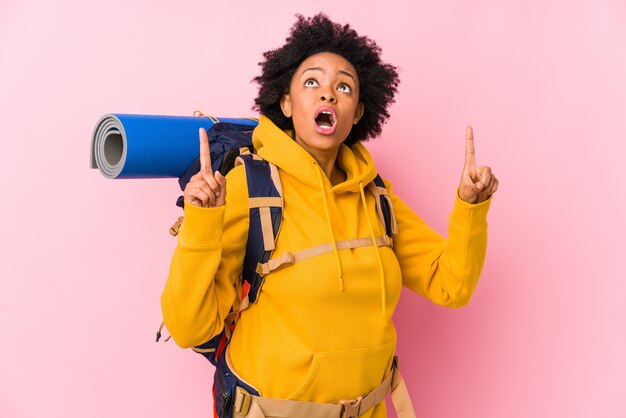 A mulher afro-americano nova do mochileiro isolou apontar a cabeça com boca aberta.