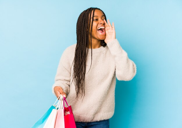 A mulher afro-americano nova que guarda um saco de compras isolou a gritaria e que guarda a palma perto da boca aberta.