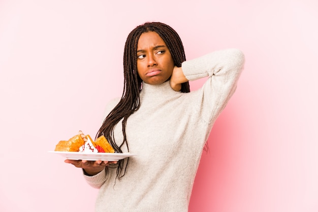 A mulher afro-americano nova que guarda um waffle isolou o toque na parte de trás da cabeça, pensando e fazendo uma escolha.