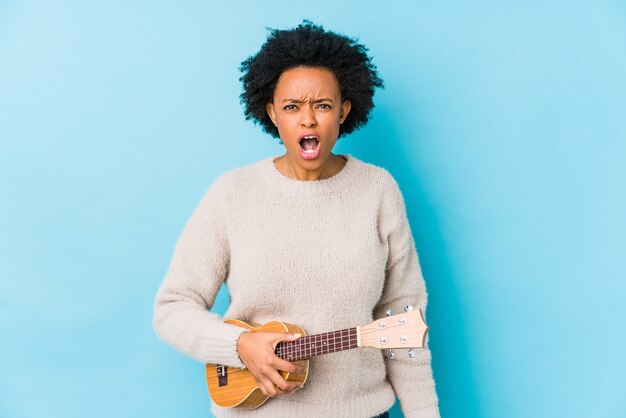 A mulher afro-americano nova que joga o ukelele isolou-se gritando muito irritado e agressivo.