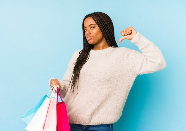 A mulher afro-americano nova que mantem uma sacola de compras isolada sente orgulhosa e auto-confiante, exemplo a seguir.