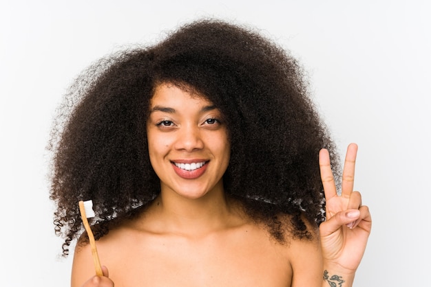 A mulher afro nova que guarda uma escova de dentes isolou mostrar o número dois com dedos.