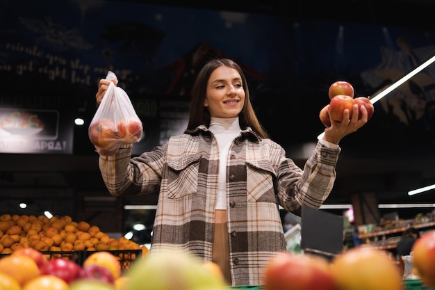 Foto a mulher amiga do ambiente compra maçãs no supermercado