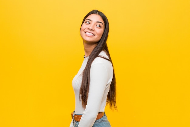 A mulher árabe bonita nova contra um fundo amarelo olha de lado o sorriso, alegre e agradável.