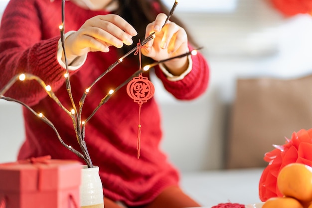 Foto a mulher asiática decorou a casa para as celebrações do ano novo chinês, colocando o pingente tradicional no ano novo lunar chinês para dar boa sorte a palavra chinesa significa bênção